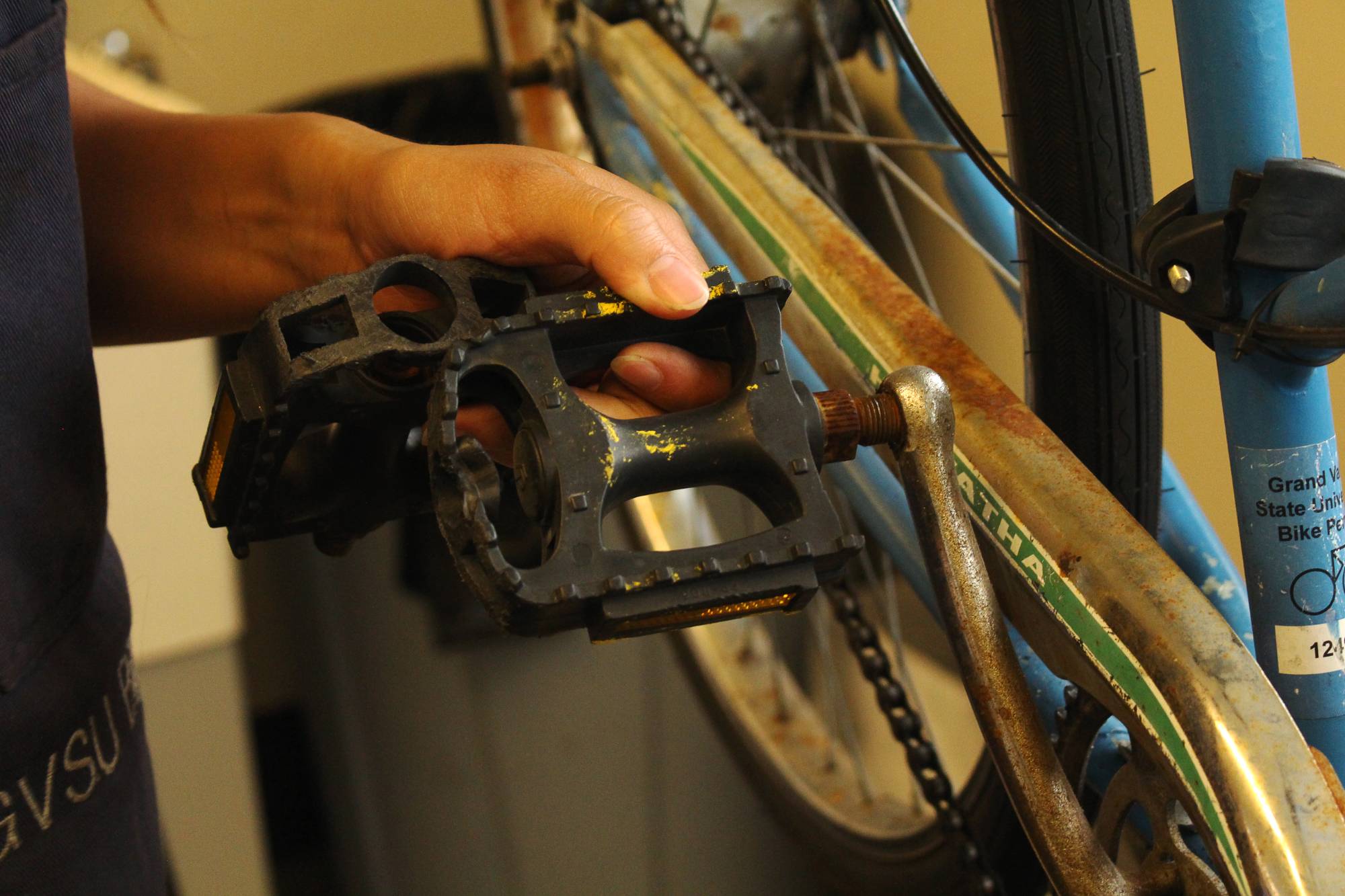 mechanic holding bike pedal that is about to fall off